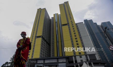 Seorang pengamen badut berdiri dengan latar belakang RSDC Wisma Atlet Kemayoran, Jakarta, Kamis (16/12). Menteri Kesehatan Budi Gunadi Sadikin mengumumkan satu kasus positif Covid-19 akibat penularan varian B.1.1.529 atau Omicron di Indonesia, yang terdeteksi berasal dari pekerja kebersihan di RSDC Wisma Atlet Kemayoran berdasarkan hasil pemeriksaan Balitbangkes dan diuji genome.