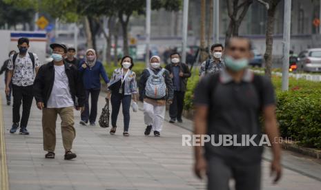 Pekerja berjalan melintasi trotoar saat jam pulang kerja di kawasan Sudirman, Jakarta, Selasa (1/11/2022). Presiden Joko Widodo (Jokowi) telah meneken Peraturan Pemerintah Pengganti Undang-Undang (Perppu) Nomor 2 Tahun 2022 tentang Cipta Kerja.