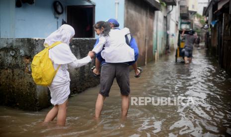 Pelajar berjalan melewati banjir di kawasan Petogogan, Jakarta. Akibat hujan deras yang mengguyur DKI Jakarta, sebanyak 12 RT terendam banjir.