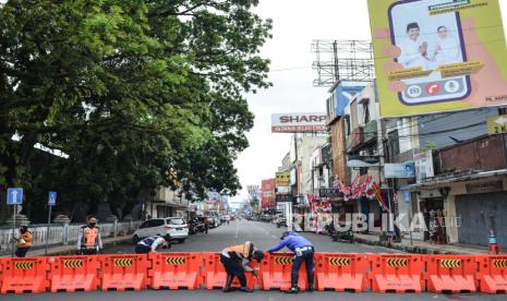 Petugas Dinas Perhubungan dan Polisi menyusun pembatas jalan atau water barier saat penutupan di Jalan KHZ Mustofa, Kota Tasikmalaya, Jawa Barat, Ahad (27/6/2021). Pemerintah Kota Tasikmalaya melakukan langkah tegas menutup jalan di pusat kota atau pertokoan untuk mengantisipasi kerumunan dan mengurangi aktivitas warga di tengah lonjakan kasus COVID-19. 