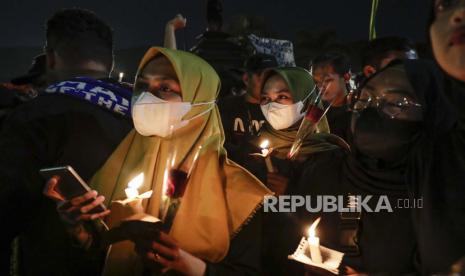 Orang-orang memegang lilin saat doa massal untuk para korban penyerbuan Stadion Kanjuruhan di Malang, Jawa Timur, Indonesia, 05 Oktober 2022. Presiden Indonesia telah memerintahkan penyelidikan dan audit ke semua stadion sepak bola di tanah air, untuk memastikan keamanan bagi Pendukung setelah sedikitnya 131 orang tewas dalam kerusuhan dan penyerbuan menyusul pertandingan sepak bola antara Arema FC dan Persebaya Surabaya di Jawa Timur pada 01 Oktober 2022.