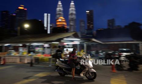 Seorang pengendara sepeda motor memakai masker dengan latar belakang Menara Kembar di pusat kota Kuala Lumpur, Malaysia, Senin, 11 Januari 2021. Perdana Menteri Muhyiddin Yassin mengatakan sistem perawatan kesehatan Malaysia berada pada titik puncak saat ia mengumumkan pembatasan pergerakan baru, termasuk di -lockdown di Kuala Lumpur dan beberapa negara berisiko tinggi untuk mengendalikan lonjakan kasus virus corona.