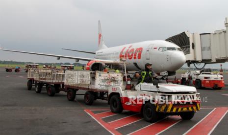 Seorang petugas mengendarai kendaraan troli bagasi di samping pesawat udara di apron Bandara Internasional Juanda, Sidoarjo, Jawa Timur.