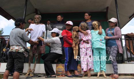 Kerabat mengganti pakaian jenazah keluarganya saat ritual Manene di Lembang Ampang Batu, Kabupaten Toraja Utara, Sulawesi Selatan, Senin (15/8/2022). Ritual yang digelar secara turun temurun oleh masyarakat Toraja tersebut untuk mengganti dan membersihkan jenazah keluarga sebagai bentuk penghormatan dan kasih sayang terhadap leluhur mereka. 