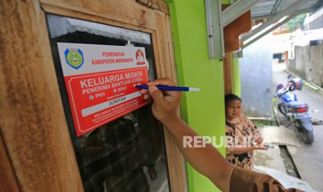 Petugas menempelkan stiker Keluarga Miskin di salah satu rumah Keluarga Penerima Manfaat (KPM) bantuan sosial di Indramayu, Jawa Barat, Senin (26/12/2022). (Ilustrasi)