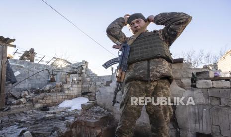 Seorang tentara Ukraina menyesuaikan senjatanya di dekat rumah yang hancur di garis pemisah dari pemberontak pro-Rusia, Donetskregion, Ukraina, Sabtu, 8 Januari 2022. 