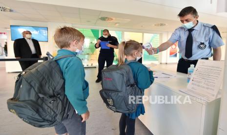 Seorang pegawai sekolah memeriksa suhu tubuh siswa di World International School of Turin, Italia (ilustrasi).