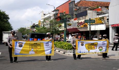 Anggota Kepolisian membawa spanduk saat mengikuti kampanye penggunaan masker 