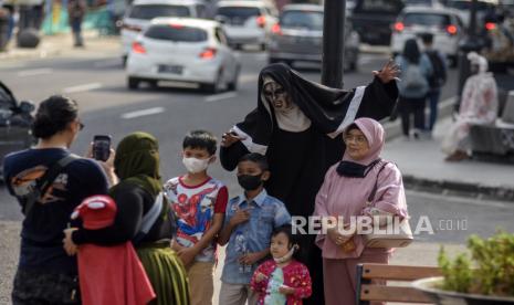 Sejumlah warga berfoto dengan cosplayer di Jalan Asia Afrika, Kota Bandung, Rabu (18/5/2022). Satuan Tugas (Satgas) Penanganan Covid-19 memastikan Indonesia resmi masuk masa transisi dari pandemi menjadi endemi Covid-19. Kondisi itu ditandai dengan sejumlah relaksasi aktivitas masyarakat dan protokol kesehatan Covid-19 seperti penghapusan kebijakan pemeriksaan PCR atau antigen bagi pelaku perjalanan, serta memperbolehkan masyarakat untuk tidak memakai masker di ruang terbuka. Foto: Republika/Abdan Syakura