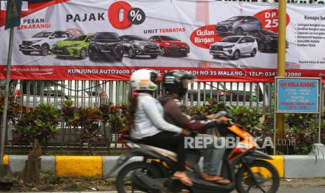 Pengendara motor melintas di depan spanduk yang memuat materi promosi pembelian mobil dengan relaksasi Pajak Penjualan Atas Barang Mewah (PPnBM) di depan diler Toyota Auto2000, Malang, Jawa Timur, Senin (1/3/2021).Pemerintah melalui Kementerian Koordinator Bidang Perekonomian memberlakukan kebijakan relaksasi Pajak Penjualan Atas Barang Mewah (PPnBM) dengan syarat tertentu yang diterapkan secara bertahap yakni mulai pada bulan Maret hingga Desember 2021. 