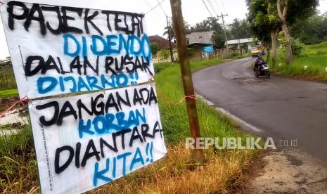 Spanduk protes jalan rusak dipasang oleh warga di Jalan Nyangkringan, Banyurejo, Sleman, Yogyakarta, Kamis (23/2/2023). Warga memasang spanduk protes ini akibat rusaknya jalan penghubung Banyurejo-Tempel yang berpotensi membahayakan pengguna jalan. Rusaknya jalan provinsi di Banyurejo ini selain karena merupakan jalur alternatif yang sering dilewati warga juga imbas dari proyek tol Jogja-Bawen.