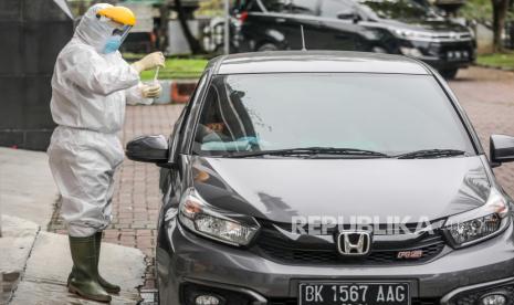  Seorang petugas layanan kesehatan dengan jas hazmat mengumpulkan sampel spesimen dari pengendara kendaraan melalui area pengujian usap COVID-19 di Medan, Sumatera Utara, Indonesia, 25 Januari 2021. Indonesia telah mencatat hampir satu juta kasus penyakit virus korona (COVID-19) sejak awal pandemi.