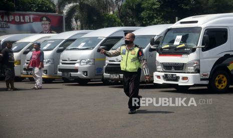 Seorang polisi melintas di depan mobil travel gelap yang terjaring dalam operasi khusus di titk penyekatan di Polda Metro Jaya, Jakarta, Senin (11/5). Dalam kurun waktu tiga hari operasi khusus tersebut, yakni mulai 8-10 Mei, Polda Metro Jaya mengamankan 202 kendaraan travel gelap yang mencoba mengangkut pemudik ke luar dari Jakarta