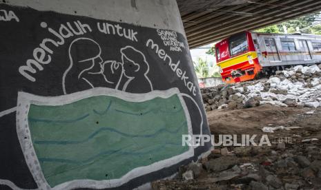 KRL melintas di dekat mural bertema pencegahaan penyebaran virus Corona atau COVID-19 di Jakarta, Rabu (1/4/2020). Mural tersebut bertujuan untuk menghimbau kepada masyarakat untuk menjaga jarak atau 