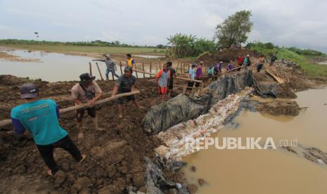 Warga secara bergotong royong memperbaiki tanggul sungai Cipanas yang jebol di desa Puntang, Losarang, Indramayu, Jawa Barat, Ahad (14/2/2021). Perbaikan darurat tanggul jebol tersebut dilakukan untuk mencegah banjir susulan yang mengancam ratusan rumah penduduk dan puluhan hektare sawah.