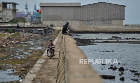 Warga beraktivitas di area tanggul Muara Baru, Jakarta, Senin (2/1/2023). Menurut Pengamat Tata Kota Nirwono Yoga mengatakan keberadaan tanggul laut raksasa atau giant sea wall dinilai tak mampu atasi banjir rob di pesisir Jakarta. Namun menurutnya, reforestasi hutan mangrove merupakan benteng alami yang ramah lingkungan guna mengatasi banjir rob tersebut. Republika/Thoudy Badai