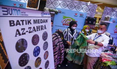 Karyawan melayani warga saat melihat batik motif batak pada gelaran Festival UMKM Toba Vaganza di Mall Centre Point, Kota Medan, Sumatera Utara, Senin (15/11/2021). Acara tersebut diselenggarakan oleh OJK dalam rangka mendukung pemerataan pemulihan perekonomian nasional dan bertujuan untuk membina para Pelaku UMKM binaan OJK untuk menghadapi pasar global. 