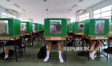 Siswa sekolah Sam Khok mengenakan masker wajah dan pelindung wajah terlihat di dalam kotak suara tua yang dipecah menjadi beberapa partisi saat mereka menghadiri kelas setelah pemerintah Thailand melonggarkan langkah-langkah isolasi dan memperkenalkan jarak sosial untuk mencegah penyebaran penyakit coronavirus (Covid-19), sebagai sekolah yang dibuka kembali secara nasional, di provinsi Pathum Thani, Thailand, 1 Juli 2020. 