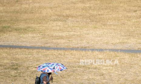 Seorang wanita menggunakan payung untuk melindungi dirinya dari matahari di Greenwich Park, London.