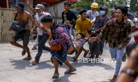 Pengadilan Myanmar Tunda Sidang Aung San Suu Kyi. Pengunjuk rasa anti-kudeta membawa seorang pria yang terluka ketika polisi anti huru hara dan tentara ditembak dengan peluru karet untuk menumpas demonstrasi di Yangon, Myanmar Minggu, 14 Maret 2021.