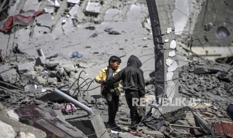 Anak-anak Palestina berdiri di reruntuhan rumah yang hancur setelah serangan udara Israel di kota Deir Al Balah di selatan Jalur Gaza, (13/3/2024).