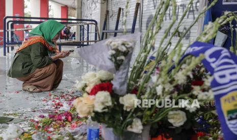 Kerabat berdoa saat dia memberikan belasungkawa untuk para korban kerusuhan dan penyerbuan di depan tribun pintu masuk 13, tempat utama penyerbuan, di Stadion Kanjuruhan di Malang, Jawa Timur, Indonesia, 06 Oktober 2022. Presiden Indonesia telah memerintahkan penyelidikan dan audit ke seluruh stadion sepak bola di tanah air, untuk memastikan keamanan bagi para penggemar setelah setidaknya 131 orang tewas dalam kerusuhan dan penyerbuan menyusul pertandingan sepak bola antara Arema FC dan Persebaya Surabaya di Jawa Timur pada 01 Oktober 2022.