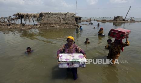 Wanita membawa barang-barang yang diselamatkan dari rumah mereka yang terendam banjir setelah hujan monsun, di distrik Qambar Shahdadkot di Provinsi Sindh, Pakistan, Selasa, 6 September 2022. Lebih dari 1.300 orang tewas dan jutaan orang kehilangan rumah mereka akibat banjir yang disebabkan oleh banjir yang tidak biasa. hujan monsun lebat di Pakistan tahun ini yang oleh banyak ahli dituding sebagai penyebab perubahan iklim.