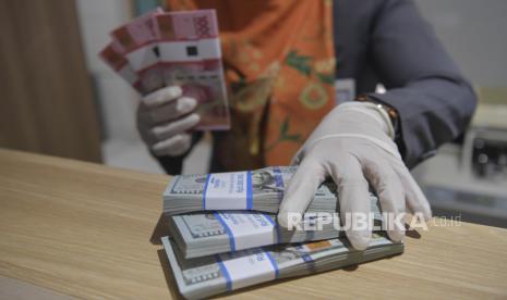 Karyawan menghitung uang rupiah dan dolar AS di Bank Mandiri Syariah, Jakarta, Senin (20/4/2020). Nilai tukar rupiah terhadap dolar Amerika Serikat (AS) menguat pada penutupan perdagangan Senin (20/4) sebesar 52 poin atau 0,34 persen ke level Rp15