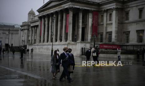  Orang-orang yang memakai masker wajah untuk mengekang penyebaran virus corona berjalan melalui Trafalgar Square dengan latar belakang Galeri Nasional, di London, Selasa, 11 Januari 2022. Confederation of Business Industry (CBI) memperkirakan perekonomian Inggris akan menyusut 0,4 persen tahun depan karena inflasi tetap tinggi