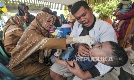 Seorang bapak menggendong anaknya yang diberikan vaksin polio tetes oleh petugas kesehatan saat Pekan Imunisasi Nasional (PIN) Polio di Posyandu Lavenda, Simpang Rimbo, Jambi, Selasa (23/7/2024). Dinas Kesehatan Kota Jambi menargetkan cakupan imunisasi sebesar 95 persen atau sebanyak 80.297 anak. 