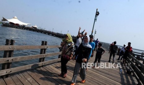 Sejumlah wisatawan berjalan di Jembatan Pantai Ancol, Jakarta, Ahad (17/6).