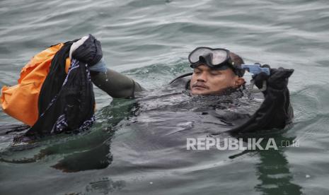 Seorang penyelam Angkatan Laut Indonesia menunjukkan puing-puing yang ditemukan dari air selama operasi pencarian jet penumpang Sriwijaya Air yang jatuh ke laut dekat Jakarta, Indonesia, Minggu, 10 Januari 2021.Penyelam Indonesia pada hari Minggu menemukan bagian-bagian dari puing-puing Boeing 737-500 di kedalaman 23 meter (75 kaki) di Laut Jawa, sehari setelah pesawat yang membawa puluhan orang di dalamnya jatuh tak lama setelah lepas landas dari Jakarta.