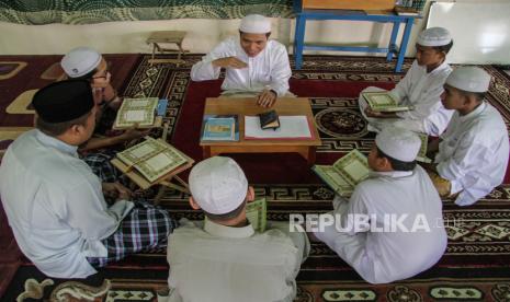 Seorang ustadz mengajarkan Alquran.  Mengajarkan ilmu juga termasuk sedekah yang utama 