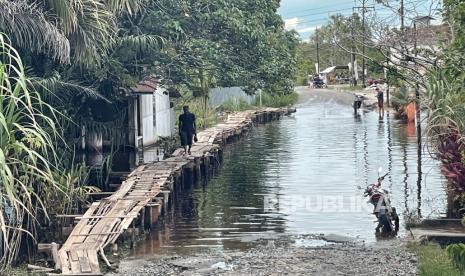 Warga berjalan di atas jembatan darurat di sebuah jalan yang terendam banjir di Kelurahan Akcaya, Kecamatan Sintang, Kabupaten Sintang, Kalimantan Barat, Sabtu (13/11/2021). Penduduk setempat membangun jembatan darurat tersebut untuk membantu pejalan kaki, pengendara motor dan pesepeda yang melintasi jalan yang terendam banjir. 