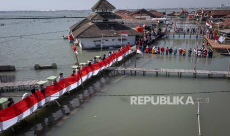 Warga mengikuti upacara bendera di perkampungan mereka yang terendam limpasan air laut ke daratan atau banjir rob di Dusun Timbulsloko, Desa Timbulsloko, Kecamatan Sayung, Kabupaten Demak, Jawa Tengah, Kamis (17/8/2023). Upacara peringatan HUT ke-78 Kemerdekaan Republik Indonesia itu warga mengampanyekan ancaman krisis iklim serta menyuarakan tuntutan penyelesaian dan solusi pemerintah mengenai masalah kerusakan lingkungan pesisir setempat yang terancam hilang tenggelam akibat kenaikan air laut disertai penurunan muka tanah. 