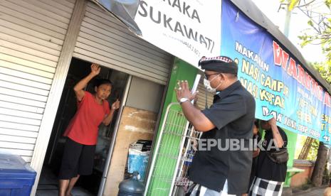 Pecalang atau petugas pengamanan adat Bali memberikan imbauan kepada masyarakat untuk menutup tempat usaha di wilayah Desa Adat Tuban, Badung, Bali, Kamis (26/3/2020). Gubernur Bali Wayan Koster mengeluarkan imbauan agar seluruh masyarakat Bali tetap berada di rumah masing-masing pada Kamis (26/3) atau satu hari setelah Hari Raya Nyepi untuk mencegah penyebaran COVID-19