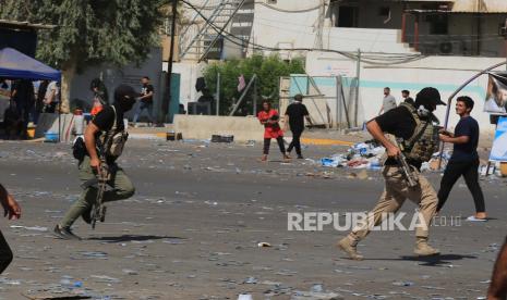  Orang-orang bersenjata Syiah Irak yang setia kepada ulama Syiah dan pemimpin gerakan Sadr Muqtada al-Sadr, bentrok dengan pasukan pemerintah yang didukung oleh kelompok-kelompok Syiah bersenjata, di Zona Hijau Baghdad tengah, Irak, 30 Agustus 2022. Sedikitnya 23 orang tewas dan ratusan lainnya luka-luka sejak bentrokan meletus pada 29 Agustus menyusul pengumuman al-Sadr untuk mundur dari politik.