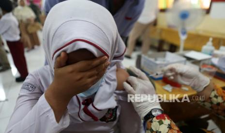 Seorang siswa sekolah dasar bereaksi ketika petugas kesehatan menyuntikkan suntikan vaksin COVID-19 selama perjalanan vaksinasi untuk anak-anak berusia antara enam hingga 11 tahun, di Banda Aceh, Indonesia, 18 Januari 2022.  Epidemiolog dari Universitas Griffith Australia Dicky Budiman meminta pembelajaran tatap muka (PTM) di sekolah bisa dihentikan sementara hingga awal Maret 2022 mendatang. 