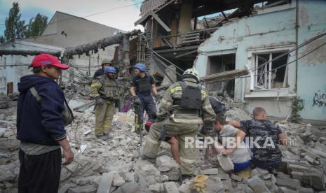 Petugas SAR dan penduduk setempat mengambil mayat dari bawah puing-puing sebuah bangunan setelah serangan udara Rusia di Lysychansk, wilayah Luhansk, Ukraina, Kamis, (16/6/2022).