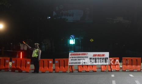 Polisi berjaga di ruas jalan Ahmad Yani yang ditutup saat pemberlakuan jam malam di Kota Banjarmasin, Kalimantan Selatan, Selasa (28/4/2020) malam. Untuk memaksimalkan Pembatasan Sosial Berskala Besar (PSBB) di Kota Banjarmasin pihak Kepolisian Resor Kota Banjarmasin memperketat pemberlakuan jam malam dengan dilakukan penyekatan jalan masuk ke dalam kota dengan akses terbatas dan penutupan jalan keluar kota pada pukul 00