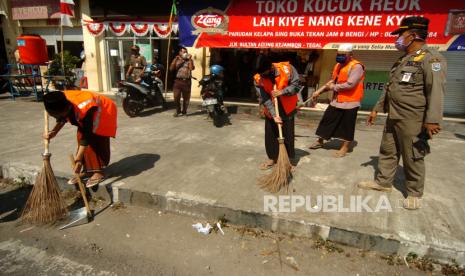 Ilustrasi. Sejumlah warga yang tidak memakai masker dan tidak membayar denda melakukan sanksi menyapu jalan saat razia masker. 