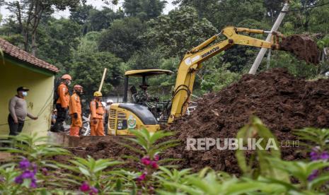 Petugas gabungan membersihkan material longsor yang menimbun rumah warga di Desa Cihanjuang, Kecamatan Cimanggung, Kabupaten Sumedang, Ahad (10/1). Longsor yang disebabkan oleh kondisi tanah tidak stabil dan curah hujan tinggi pada Sabtu (9/1) mengakibatkan sekitar 14 rumah rusak berat dan 12 orang meninggal dunia serta belasan orang lainnya masih dalam pencarian. Foto: Abdan Syakura/Republika