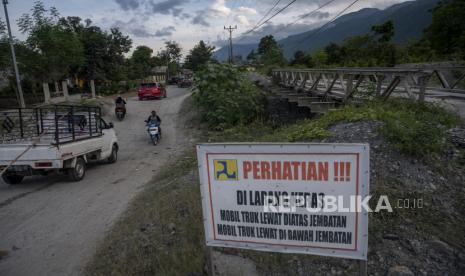 Pengendara melintas di bawah jembatan darurat yang berada di saluran pengendali banjir di Desa Beka, Sigi, Sulawesi Tengah, Kamis (7/4/2022). Sejak diterjang bencana banjir bandang September tahun lalu, jembatan yang menghubungkan Kota Palu dengan sejumlah kecamatan di Kabupaten Sigi itu tidak kunjung dibangun karena keterbatasan anggaran akibat banyaknya bencana serupa di wilayah lain di daerah tersebut.