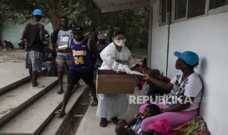 Seorang perawat membagikan masker di sebuah kamp pengungsi improvisasi di Ciudad Acua, Meksiko, Selasa, 21 September 2021. Pilihan yang tersisa untuk ribuan migran Haiti yang melintasi perbatasan Meksiko-Texas semakin menyempit ketika pemerintah Amerika Serikat mencapai yang diharapkan enam penerbangan pengusiran ke Haiti, dan Meksiko mulai menggunakan bus beberapa dari perbatasan. Umat Muslim Texas Himpun Dana untuk Bantu Pengungsi