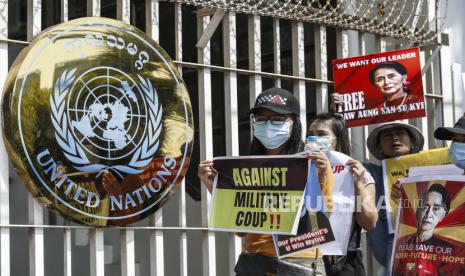 Demonstran memegang plakat di luar kantor Perserikatan Bangsa-Bangsa (PBB) selama protes melawan kudeta militer di Yangon, Myanmar, 16 Februari 2021. Junta militer Myanmar pada 16 Februari menghentikan layanan internet untuk hari kedua berturut-turut karena protes terus berlanjut meskipun pasukan telah dikerahkan dan kendaraan lapis baja di kota-kota besar.