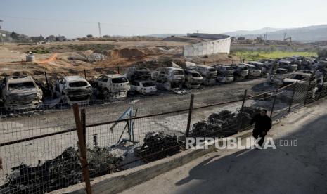 Seorang pria Palestina berjalan melewati mobil -mobil yang terbakar di kota Hawara, dekat kota Tepi Barat Nablus, Senin, 27 Februari 2023. Sejumlah pemukim Israel mengamuk dengan kekerasan di Tepi Barat Utara, membakar mobil dan rumah yang terbakar. Setelah dua pemukim terbunuh oleh seorang pria bersenjata Palestina. Pejabat Palestina mengatakan satu orang terbunuh dan empat lainnya terluka parah.