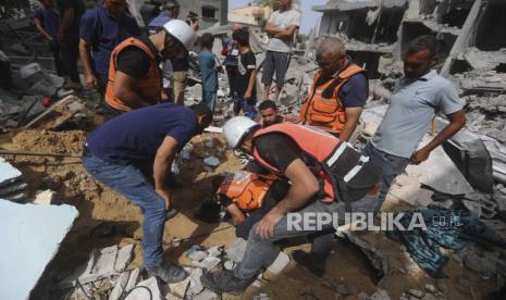 Warga Palestina mencari korban selamat setelah serangan udara Israel terhadap sebuah bangunan tempat tinggal di Kamp Pengungsi Nuseirat, Jalur Gaza, Ahad, (19/5/2024).