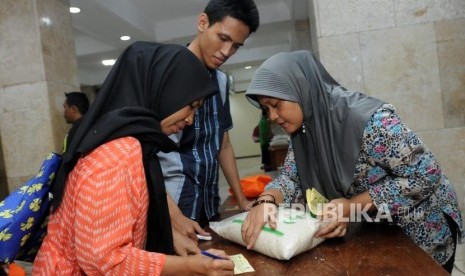 Petugas melayani warga saat pembagian zakat fitrah di Masjid Istiqlal, Jakarta, Kamis (14/6).