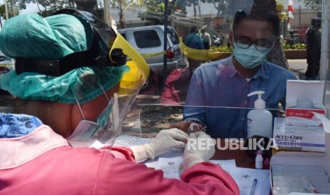 Petugas kesehatan mengambil sampel darah warga saat tes diagnostik cepat (rapid test) COVID-19 ketika terjaring operasi yustisi protokol kesehatan pencegahan penularan COVID-19 karena tidak menggunakan masker di kawasan depan Stasiun Kereta Api Kota Madiun, Jawa Timur, Kamis (17/9/2020). Pemkot Madiun menggelar operasi yustisi protokol kesehatan pencegahan penularan COVID-19, dengan sanksi membayar denda Rp50 ribu atau sanksi sosial menyemprot cairan disinfektan di sekitar lokasi operasi.