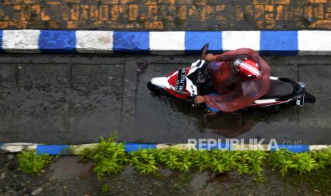 Seorang pengendara mengenakan jas hujan saat menerobos hujan. Sembilan Daerah di Kaltim Diprakirakan Hujan Petir pada Rabu-Kamis